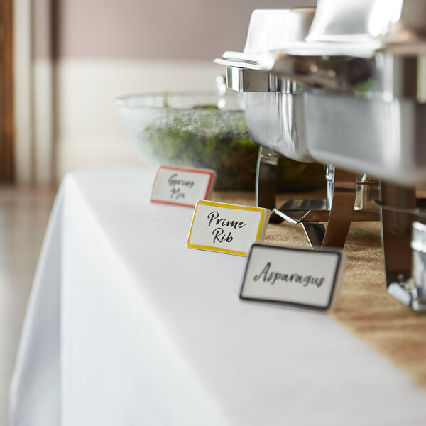 A yellow ceramic table tent sign with a border on a table in a catering event.