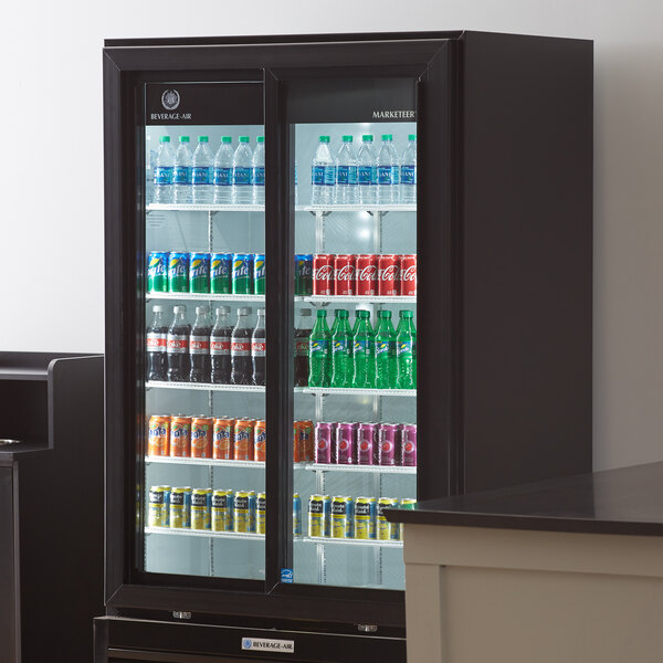 A Beverage-Air black refrigerated glass door merchandiser with soda and cans inside.