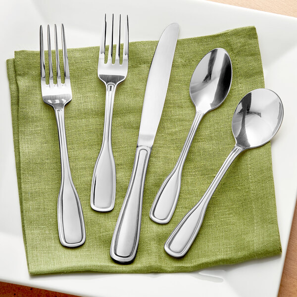 A green plate with Acopa Saxton stainless steel flatware on a napkin.