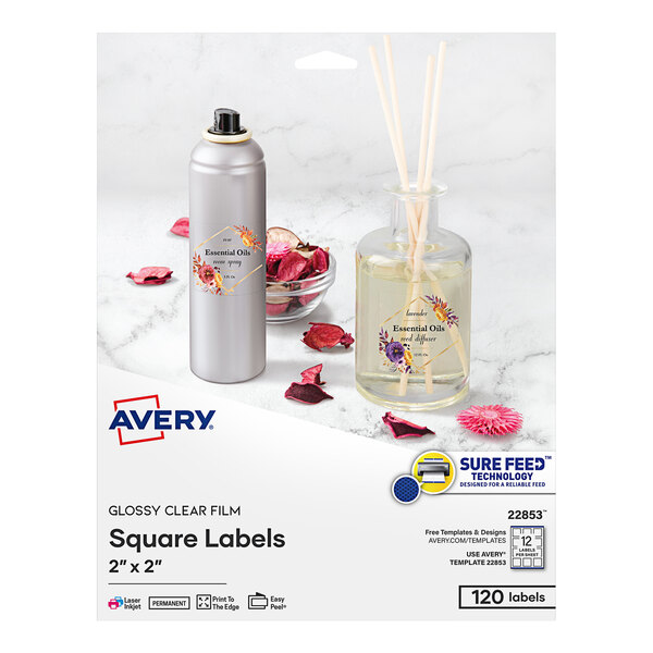 A box of Avery glossy clear square labels on a kitchen counter with a bottle of essential oil and a bowl of dried fruit.