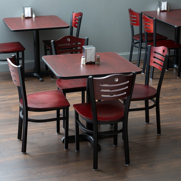 A Lancaster Table & Seating dining set with mahogany chairs on a table in a restaurant.