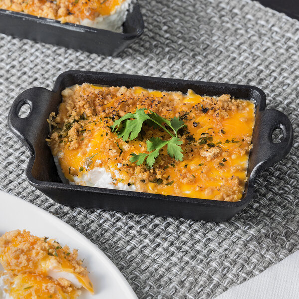 A Lodge mini cast iron rectangular casserole dish filled with cheesy chicken casserole on a table.