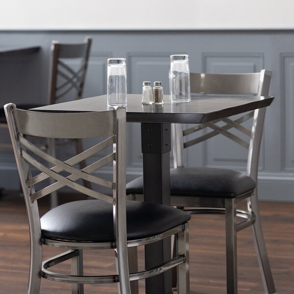 A Lancaster Table & Seating solid wood table top with two chairs and a glass of water on it.