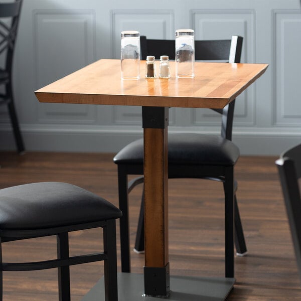 A Lancaster Table & Seating live edge wood table top with an antique natural finish on a table with empty glasses.