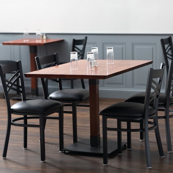 A Lancaster Table & Seating live edge dining table with mahogany finish and black chairs around it in a restaurant.