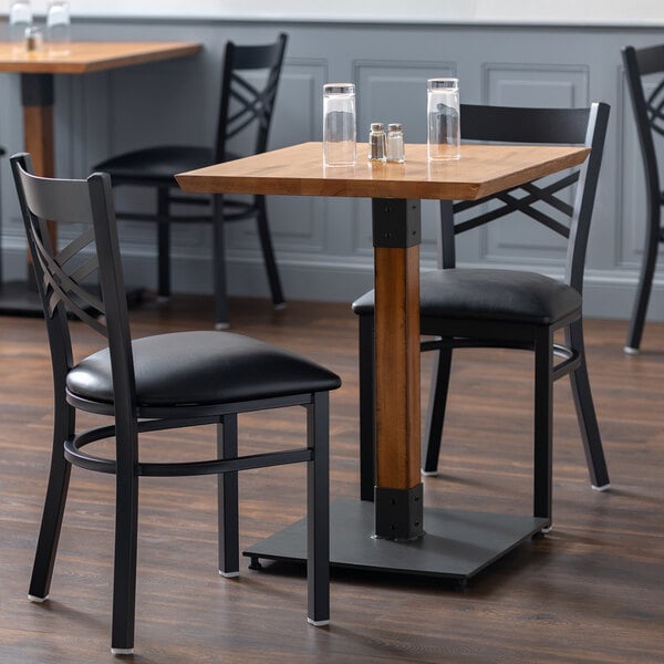A Lancaster Table & Seating wooden table in a restaurant with two black chairs.