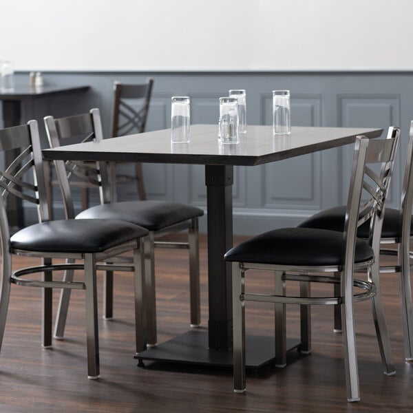 A Lancaster Table & Seating solid wood dining table with an antique slate gray finish and chairs around it.