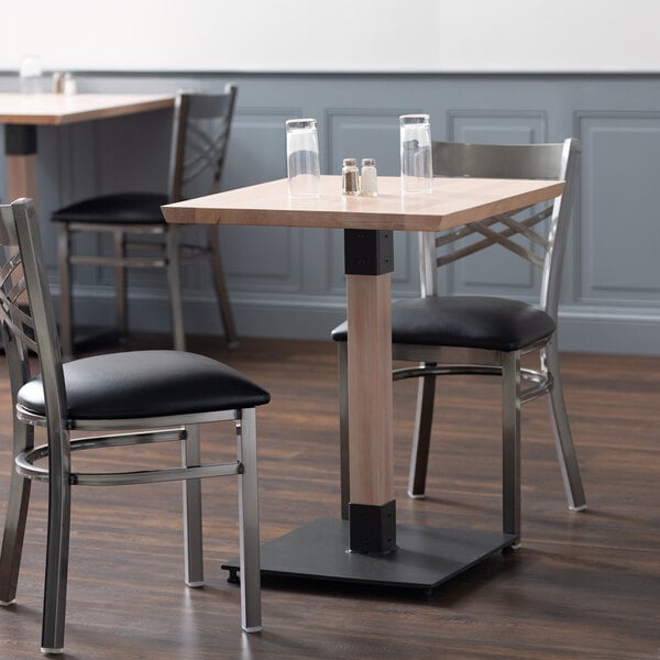 A Lancaster Table & Seating industrial wooden dining table base in a restaurant with two chairs.
