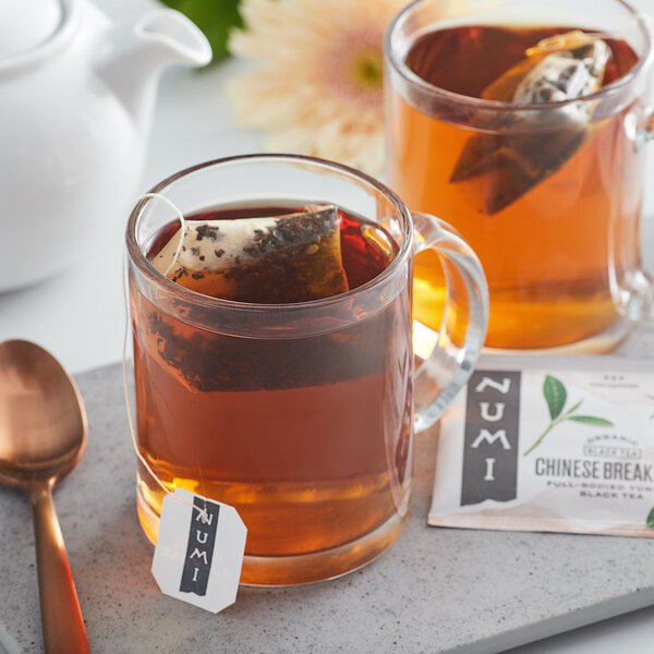 A glass mug of Numi Organic Chinese Breakfast Tea with a tea bag in it.