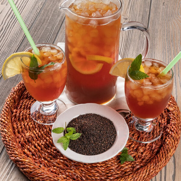 A pitcher of Numi iced tea with lemons and mint leaves on a wicker tray.