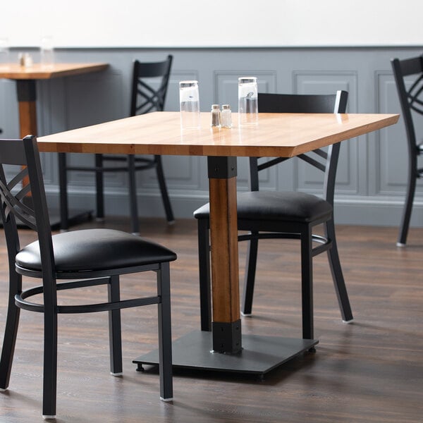 A Lancaster Table & Seating solid wood table with a live edge top and antique finish with chairs in a restaurant dining area.