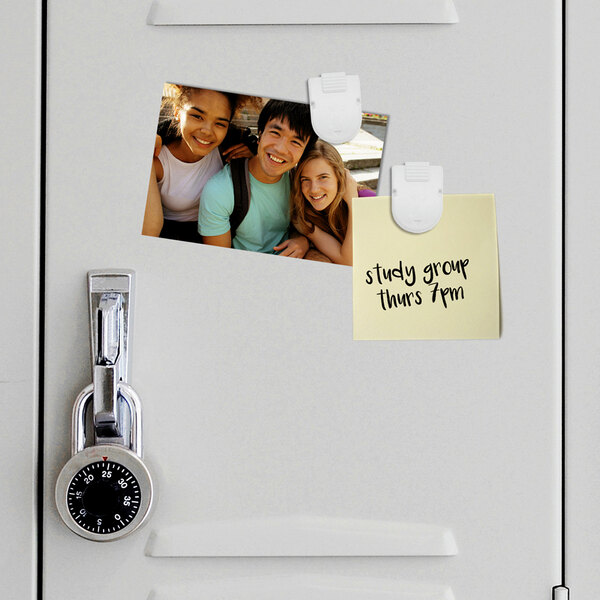 A white magnetic clip holding a photo on a locker.