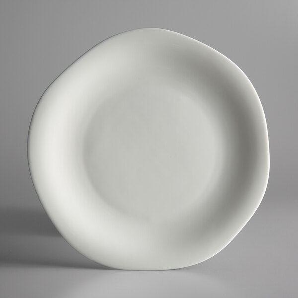 A Oneida Lancaster Garden white porcelain plate with a curved edge on a gray surface.