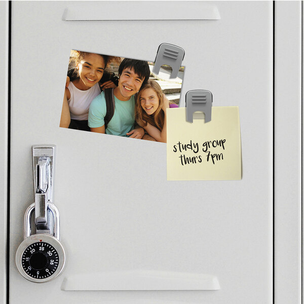 A gray magnetic clip on a locker with a photo of a group of people.