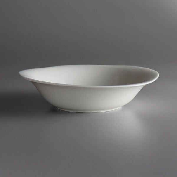 A white Oneida Lancaster Garden porcelain bowl with a curved rim on a grey surface.