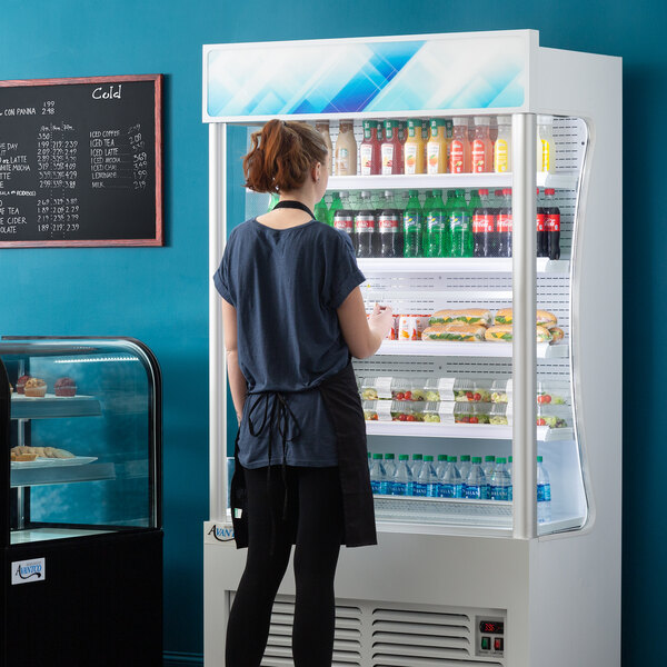 An Avantco white refrigerated air curtain merchandiser with food on display.