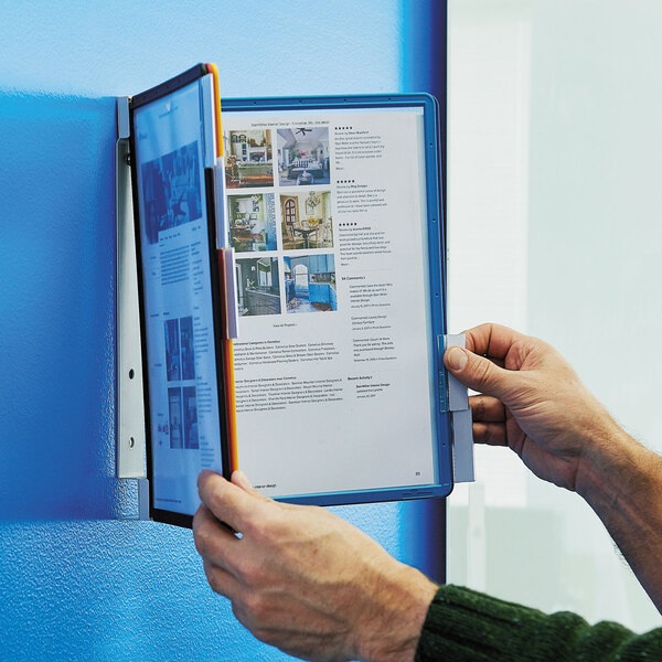 A person holding a Durable VARIO folder in front of a blue wall.
