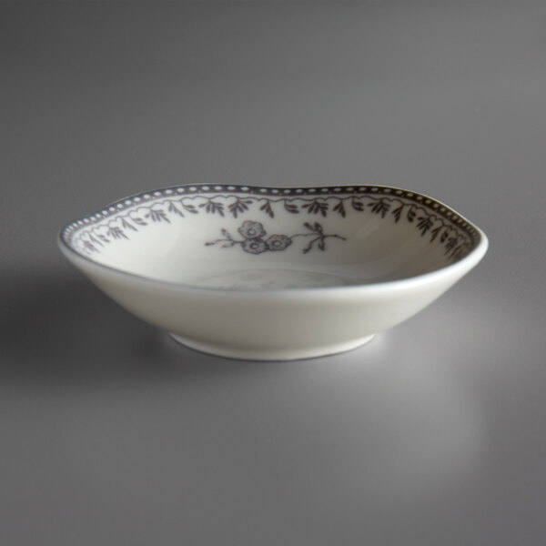 A white porcelain sauce dish with black designs.