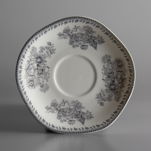 A white porcelain saucer with a grey floral design.