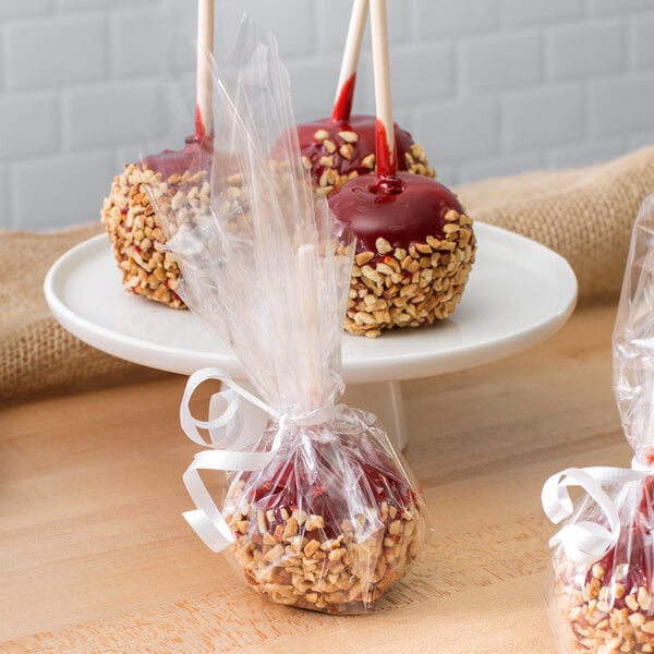 A red caramel apple wrapped in clear LK Packaging deli wrap with peanuts.