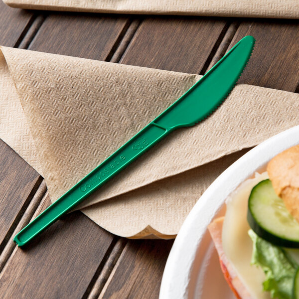 A EcoChoice green CPLA plastic knife on a napkin on a table