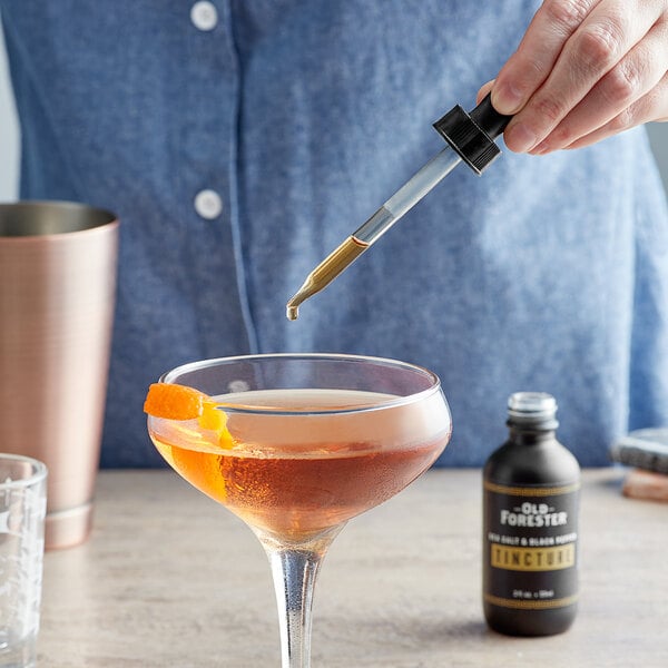 A person using Old Forester Sea Salt and Black Pepper Tincture to pour a cocktail.