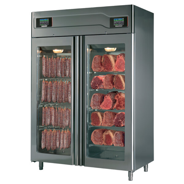A stainless steel Maturmeat meat aging and curing cabinet with glass doors full of meat.