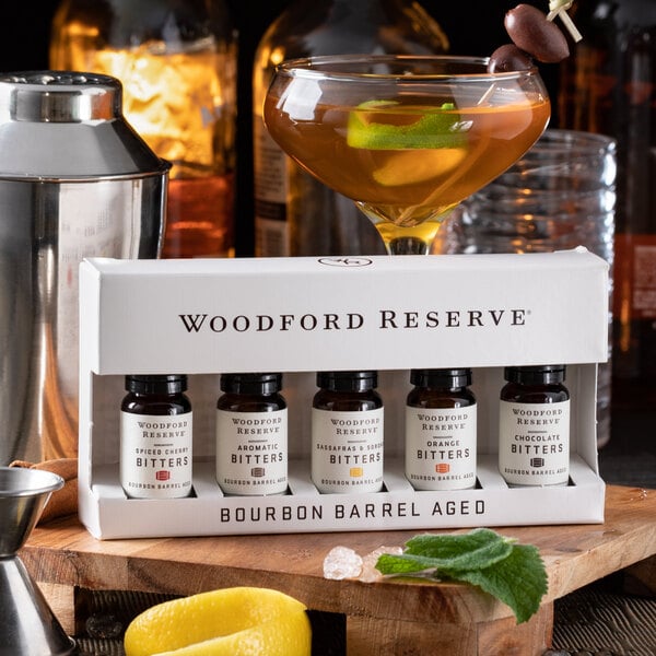A Woodford Reserve box of bourbon barrel aged bitters on a table with a martini glass.