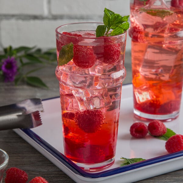A pair of Libbey Tritan plastic beverage glasses with a red drink and raspberries on a tray.