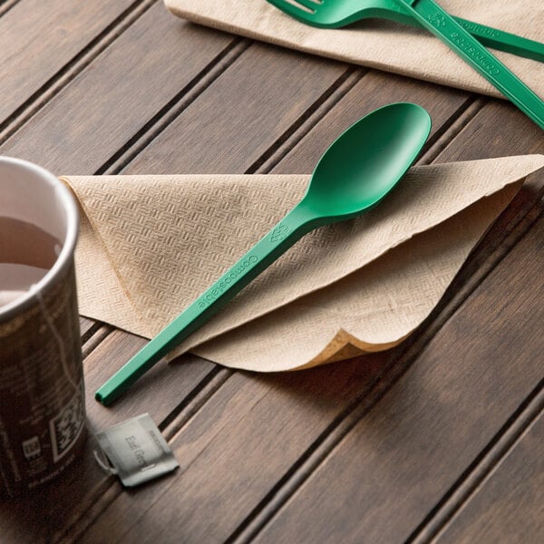 A green EcoChoice heavy weight plastic spoon on a napkin.