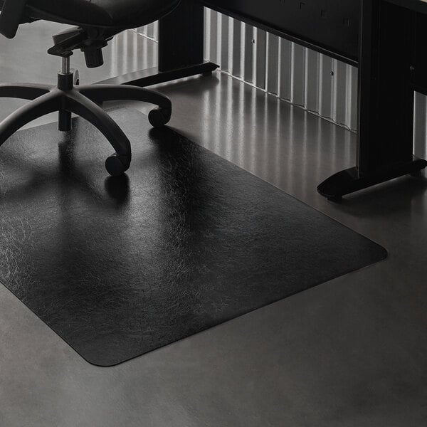 A black ES Robbins EverLife chair mat on a floor with a black office chair with wheels.