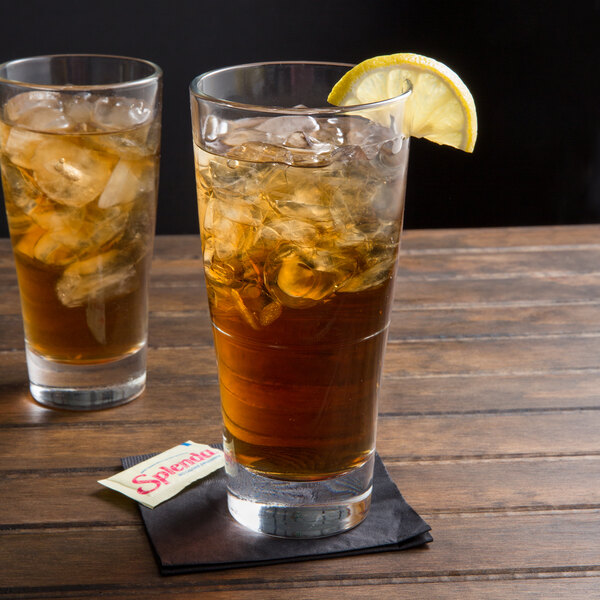 Two Arcoroc stackable beverage glasses of iced tea with lemon wedges.