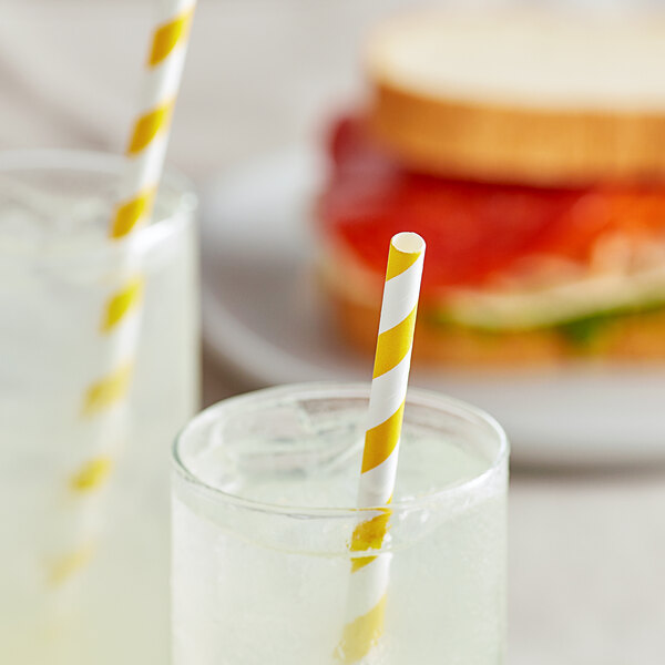 A sandwich and a drink with EcoChoice gold and white striped paper straws in the drink.