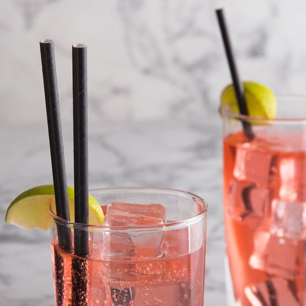 Two glasses of pink liquid with EcoChoice black paper straws on a table.