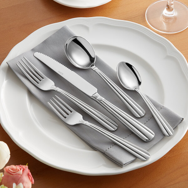 A white plate with Acopa Harmony stainless steel flatware on it.
