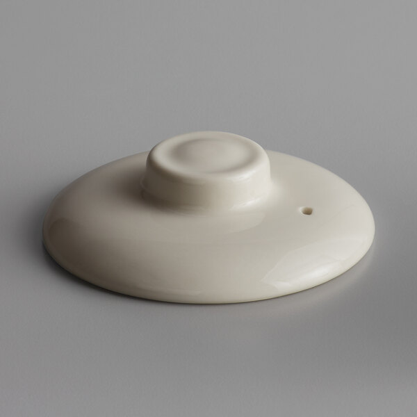 A white oval porcelain lid with a circular design in the center.