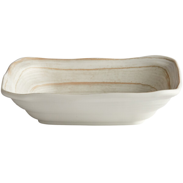 An off white irregular square bowl with a brown stripe on the edge.
