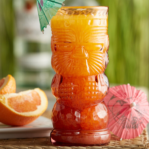 A close up of a Warrior Lava Red Tiki Glass filled with an orange drink and garnished with orange slices.