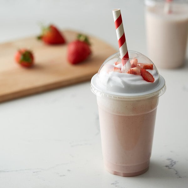 A strawberry milkshake with a red and white striped EcoChoice paper straw.