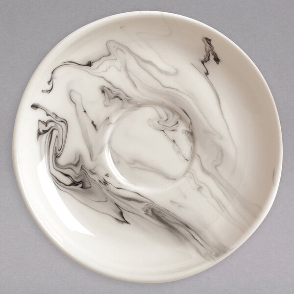 A white porcelain tea saucer with a black swirl design.