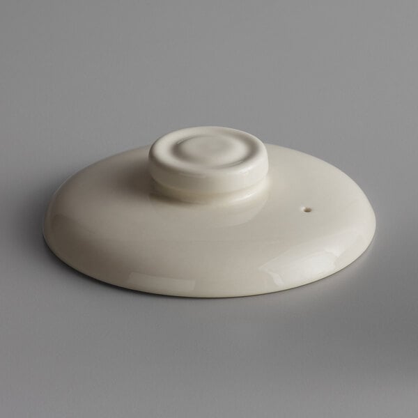A white oval porcelain lid with a circular top.