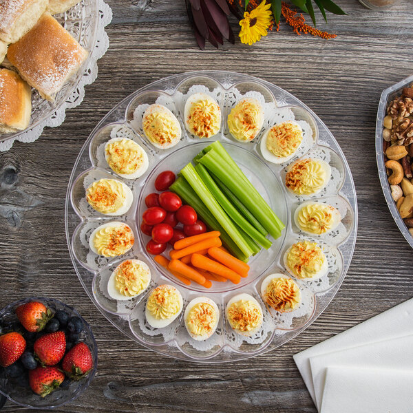A Fineline plastic egg tray with deviled eggs and vegetables on a table.
