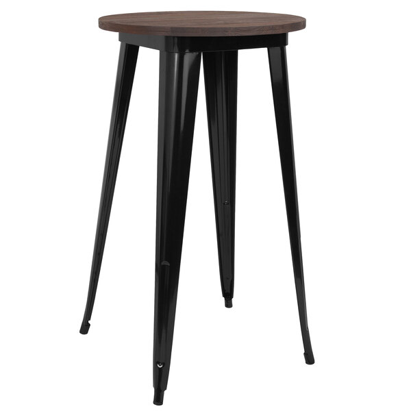 A black metal bar height table with a round walnut top.