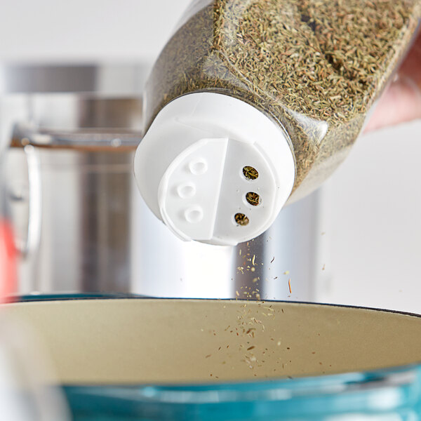 A hand using a 53/485 White Dual-Flapper Induction-Lined Spice Lid to pour seasoning into a bowl.
