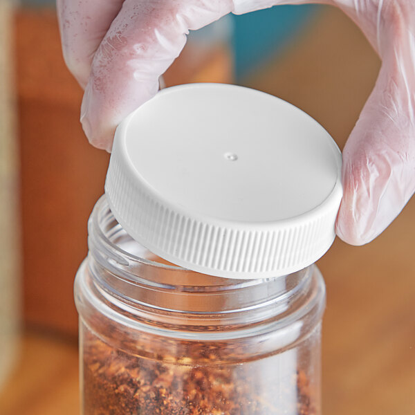 A person holding a plastic container with a white 63/485 flat top lid filled with spices.