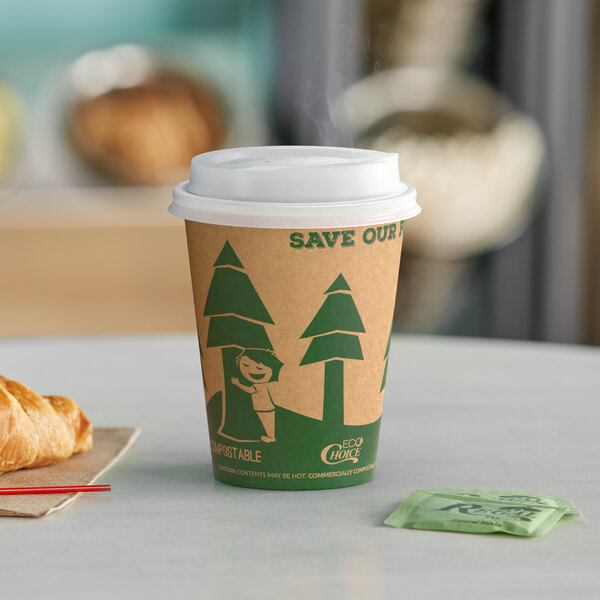 An EcoChoice paper hot cup with a Kraft tree print and a green lid on a table with a croissant.