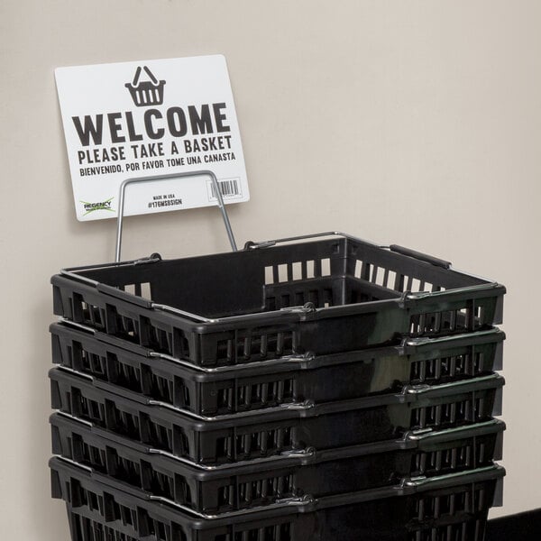 A black Regency shopping basket with a sign holder attached.