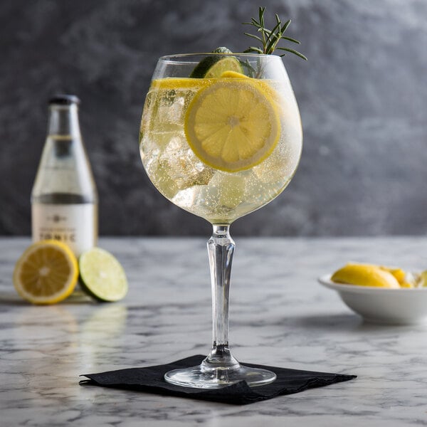 A Libbey gin and tonic glass with a slice of lemon in the drink.