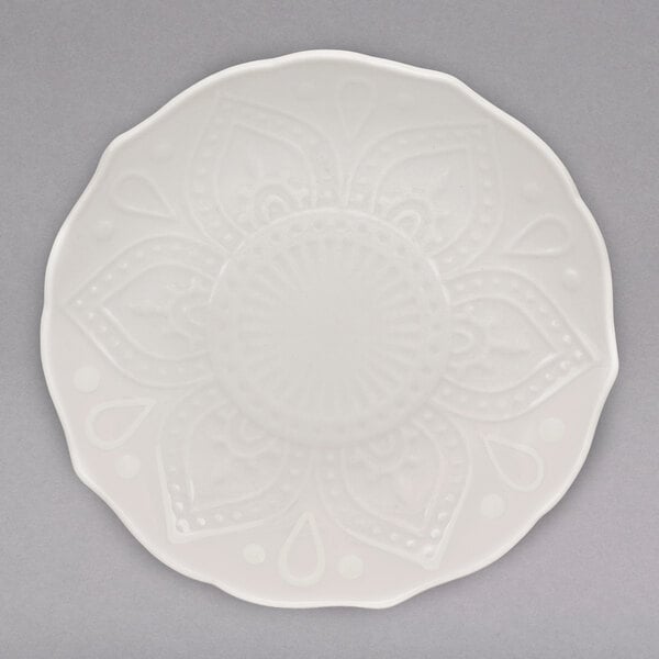 A white 10 Strawberry Street porcelain bread and butter plate with a circular flower design.