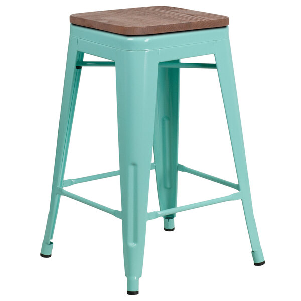 A mint green metal backless counter height stool with a wooden seat.